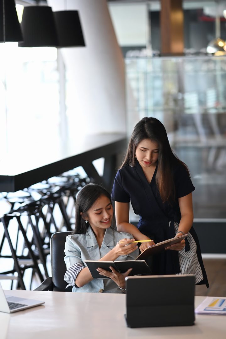 Two young businesswoman using digital tablet and discussing business plan.